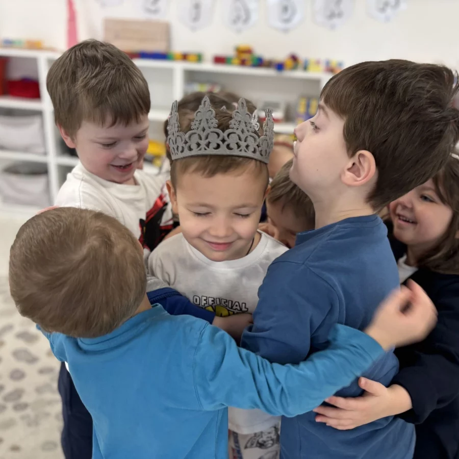 Dzieci podczas zabawy w przedszkolu SunnyKids w Krakowie - chłopiec w koronie otoczony przez przyjaciół, rozwijanie umiejętności społecznych i kreatywności w placówkach na Żabińcu i Górce Narodowej